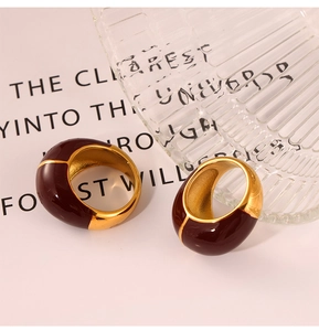 Close-up of vintage wide-band gold rings with burgundy enamel glaze and polished finish