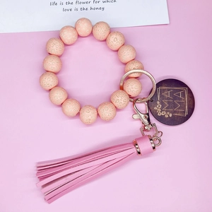 Détail du porte-clés perlé léopard rose avec breloque Mama en bois et pompon en cuir