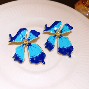 Elegant gradient blue petal earrings with gold tassels on a white ceramic plate