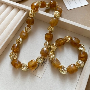 Detail of amber acrylic beads and twisted gold metal beads set in a jewelry box