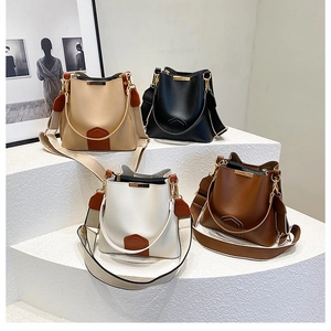 Multiple colors of retro style bucket bags with wide straps and metal trim details