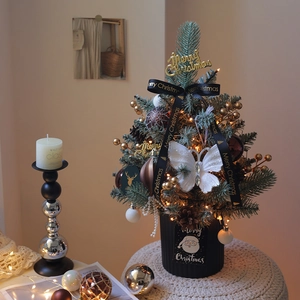 Mini artificial Christmas tree with LED lights and golden ornaments in a striped pot