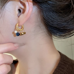 Close-up of 18k gold plated hoop earrings with tiger eye and pearl pendants on model