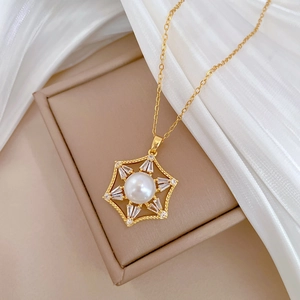 Detail of a golden hexagon star pendant with white pearl and baguette zircon accents