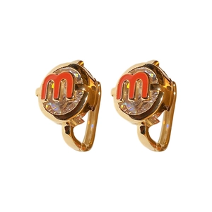 Golden hoop earrings with clear zircon and red enamel letter M on white background