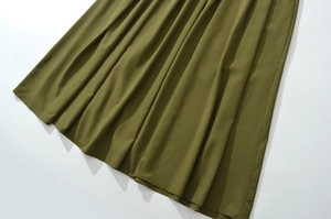 Dettaglio dell'orlo dell'abito verde oliva con pieghe eleganti e drappeggio del tessuto