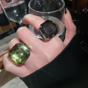 Detail of square-cut emerald green and black cocktail rings with silver four-prong setting