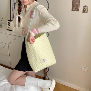 Detail of light yellow quilted tote bag with heart pattern and blue shoulder straps