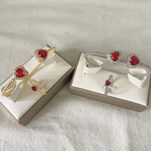 Detailed view of gold and silver jewelry sets with red heart stones and twisted bands