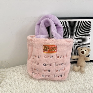 Détail du sac cabas en peluche rose avec poignées violettes et texte brodé doux