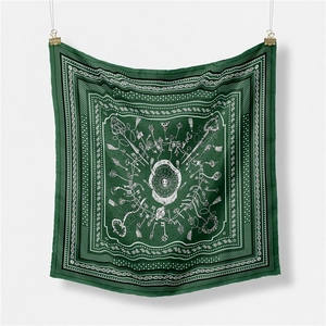 Macro detail of silk scarf with paisley patterns, tassels and keys on dark green fabric