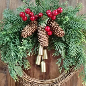 Detailed view of Christmas wreath featuring red berries, pine cones and gold bells.