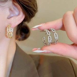 Detail of C-shaped chain-link earrings with pavé cubic zirconia in gold and silver finish