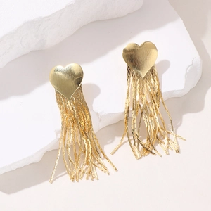 Detailed view of gold plated heart studs with dangling metal fringe tassels on stone
