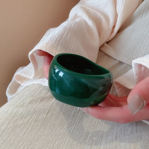Macro shot of thick dark green resin bangle with smooth irregular finish on model's hand
