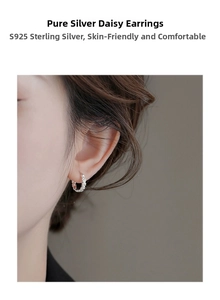 Close-up of S925 sterling silver daisy hoop earrings worn on ear with embossed flower detail