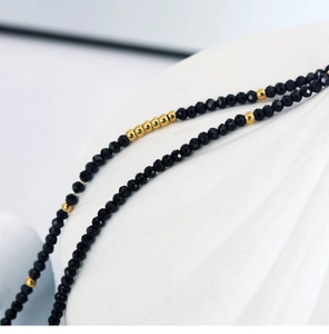 Macro shot of faceted black beads and smooth gold spheres in a layered necklace