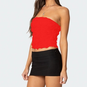 Detail eines roten Bandeau-Tops mit 3D-Blumenstruktur und schwarzem Minirock