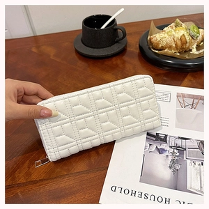 Close-up of white quilted PU leather wallet with geometric stitching on a wooden table