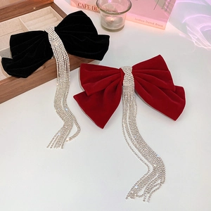 Detail of velvet bow hair clips in red and black with long rhinestone tassel fringes