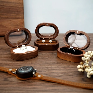 Detail view of oval walnut jewelry box with glass lid and soft velvet interior padding