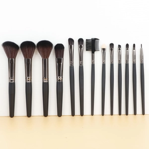 Vue à plat de 14 pinceaux de maquillage avec manches noir mat et viroles argentées