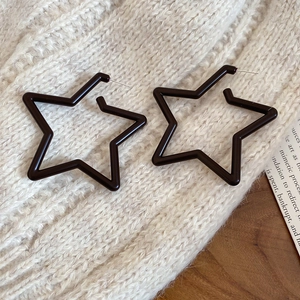 Chic black star resin earrings resting on a cozy knitted texture and wood surface