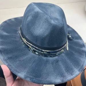 Handheld shot of a retro wide-brim jazz hat in distressed blue with ethnic ribbon decor