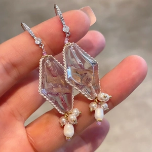 Detail of drop earrings with dried flower amber crystals and white pearls on gold plating