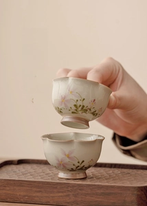 Detail of hand-painted ceramic teacups with floral patterns and minimalist wavy edges