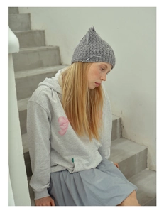 Detailed close-up of grey knit hat with bow ornament worn with casual hoodie