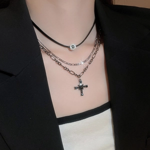 Dettaglio di una collana d'argento a strati con croce in gemma nera e riflessi brillanti