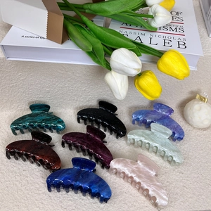 Detail view of large acetate shark hair claws in eight colors with marble textures