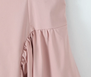 Détail de robe rose avec plis irréguliers et coutures à volants sur tissu lisse