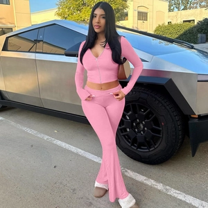 Detail of bright pink zip-up hoodie and slim fit flared pants set in an outdoor setting