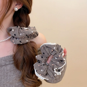 Detailed texture of gray-brown polka dot scrunchie with delicate white lace trim