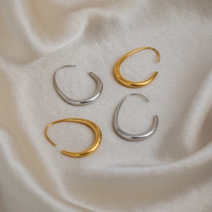 U-shaped stainless steel earrings in gold and silver finish on silk fabric background
