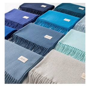 Array of colorful solid color cashmere-feel scarves with soft tassels and fine texture