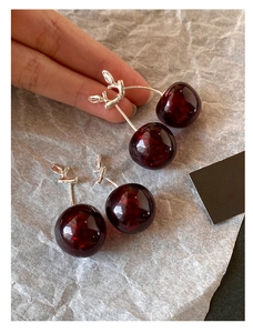 Detailed view of deep red resin cherry earrings with elegant silver leaf design