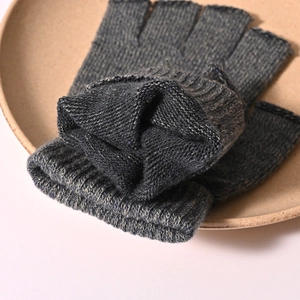 Close-up of dark grey knitted fingerless gloves with detailed wool texture on a plate