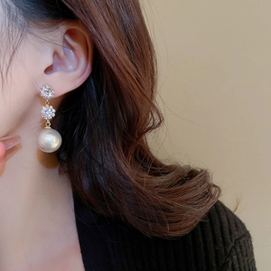 Gros plan de boucles d'oreilles dorées avec cristaux empilés et perle blanche