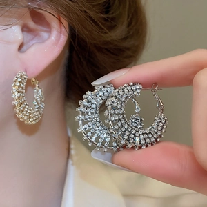 Close-up of sparkling silver-tone C-hoop earrings featuring densely set zircon crystals