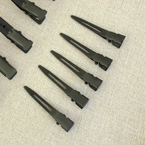 Detailed view of professional matte black metal alligator hair clips on linen fabric