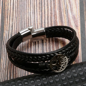 Detail of black braided leather bracelet with silver tree of life charm and magnetic clasp