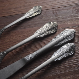 Vintage 304 stainless steel cutlery set with floral relief handles on wood background