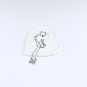 Macro shot of silver butterfly necklace and open ring on a white heart jewelry tray