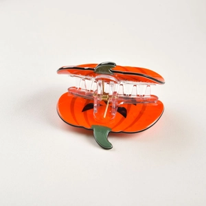 Détail d'une pince à cheveux citrouille orange avec visage de Jack-o'-lantern et tige