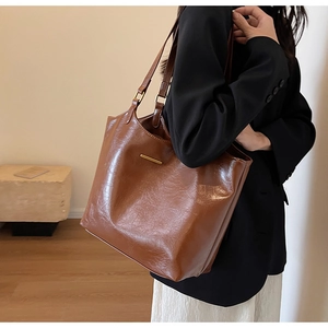 Detail of soft brown oil-wax leather tote bag featuring gold hardware and large capacity