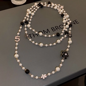 Macro shot of layered pearl necklace with camellia flowers and sparkling number 5 charms