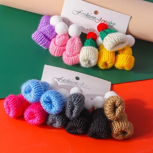 Detailed close-up of knitted mini hat earrings in vibrant colors for winter fashion